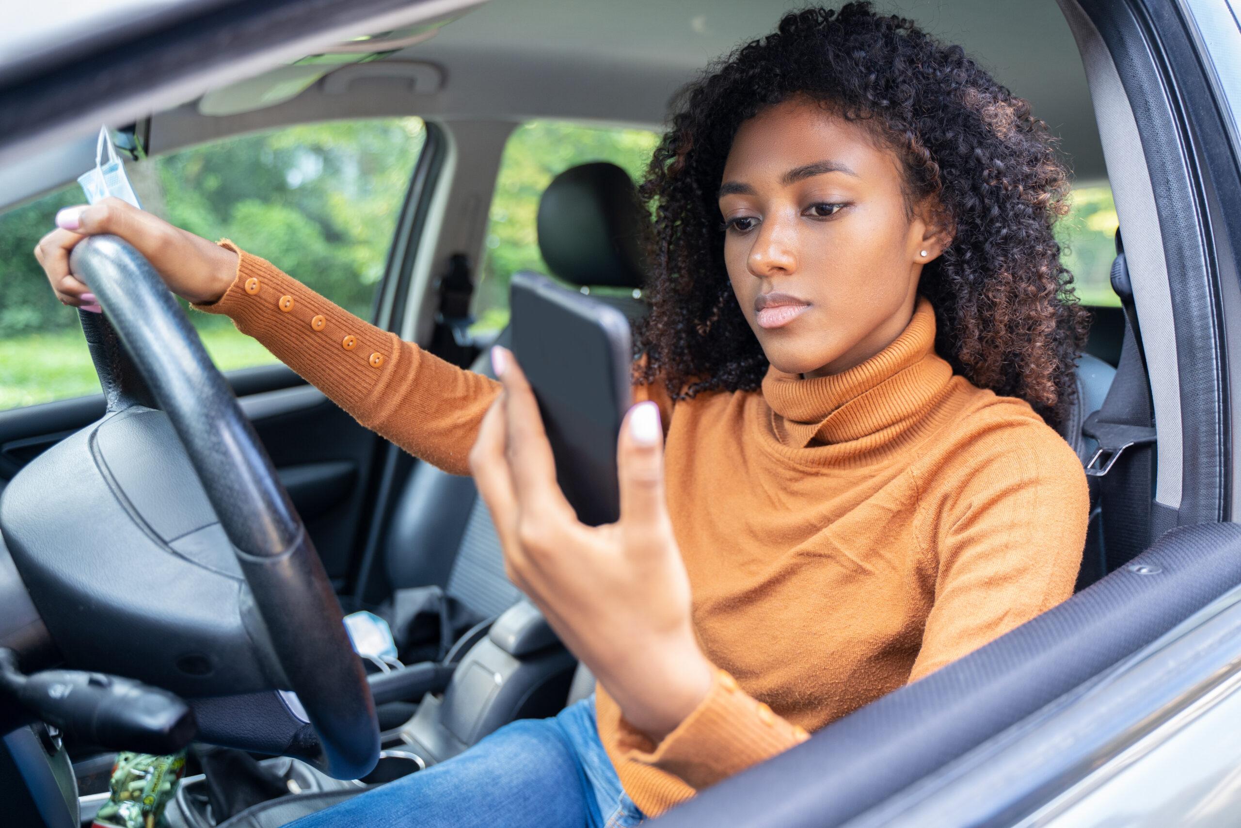 Woman driving car distracted by her mobile phone