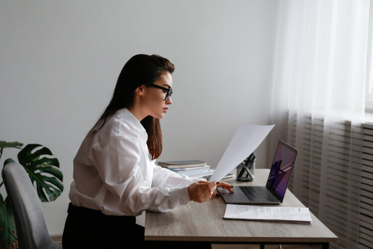 Young female lawyer wearing glasses while working on her laptop at the office.