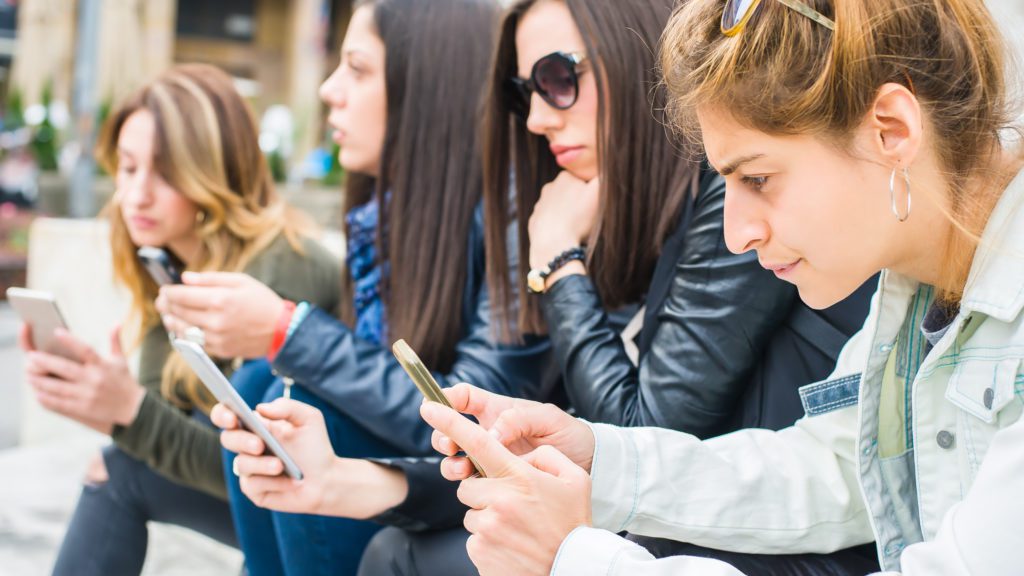 Group of girls using their smartphones outdoors.