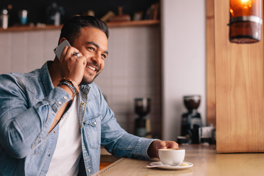 Guy sitting at a cafe while making a phone call.