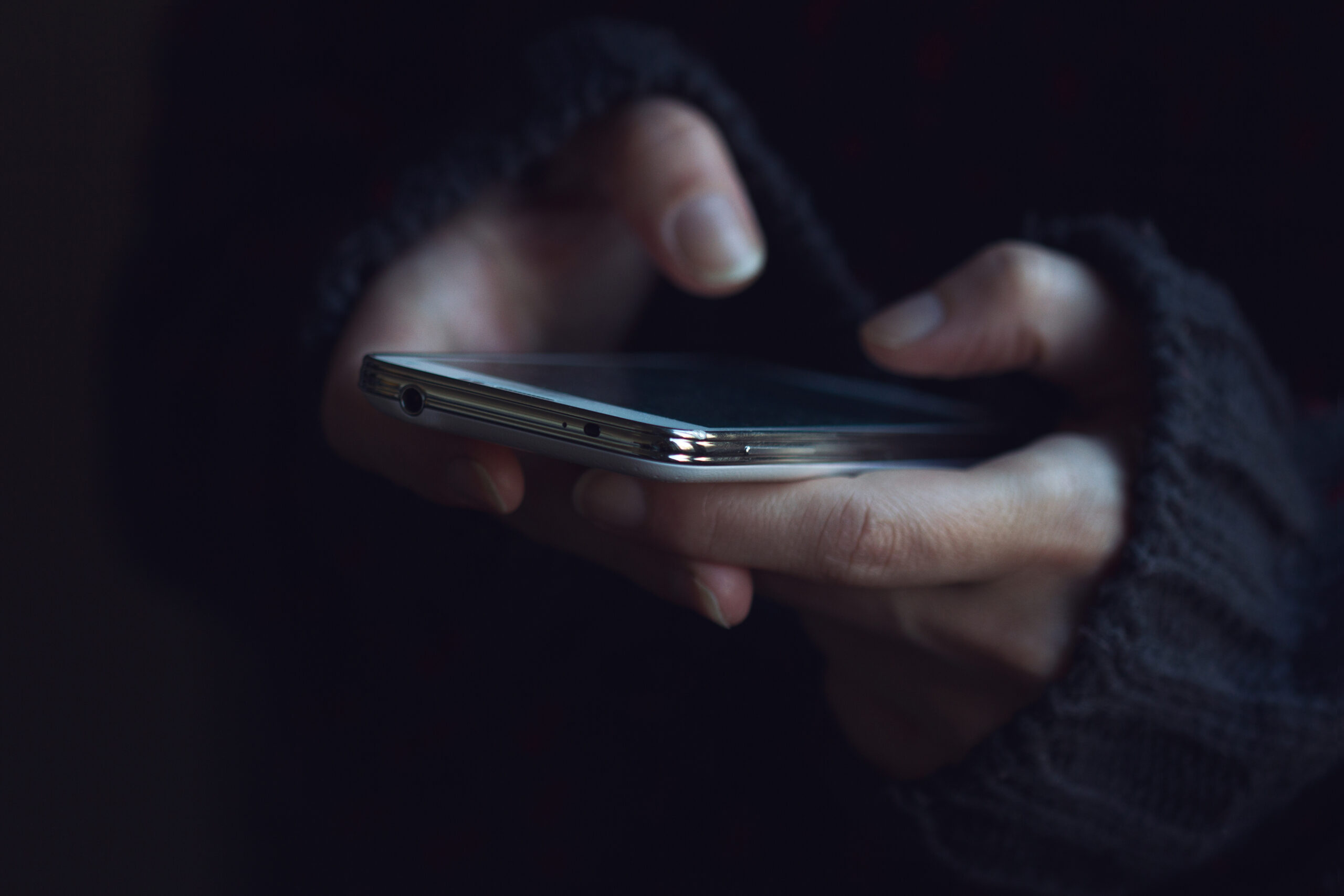 woman in dark sweater hands holding a phone