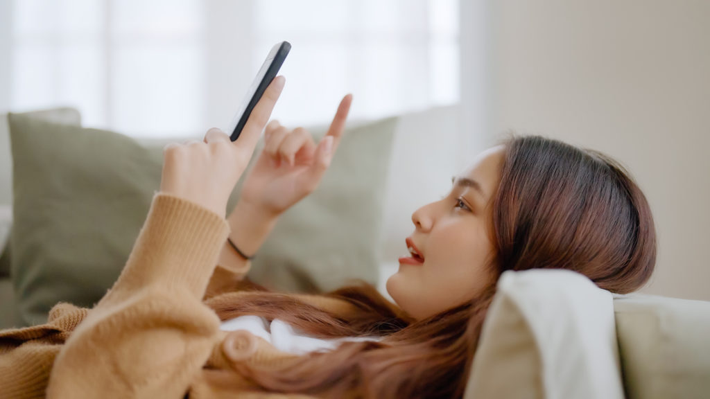 young woman relax on the couch at home using her smartphone.