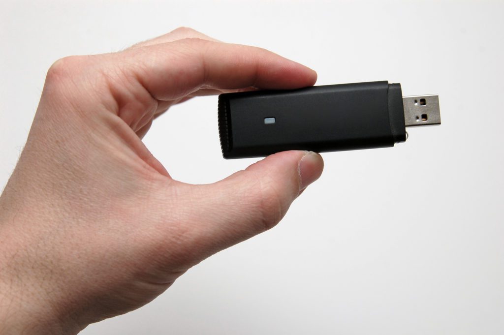 Hand with a black USB HSPA dongle.