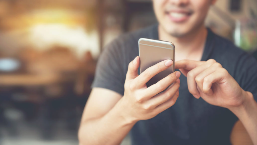 Happy man using his smartphone inside a coffee shop.