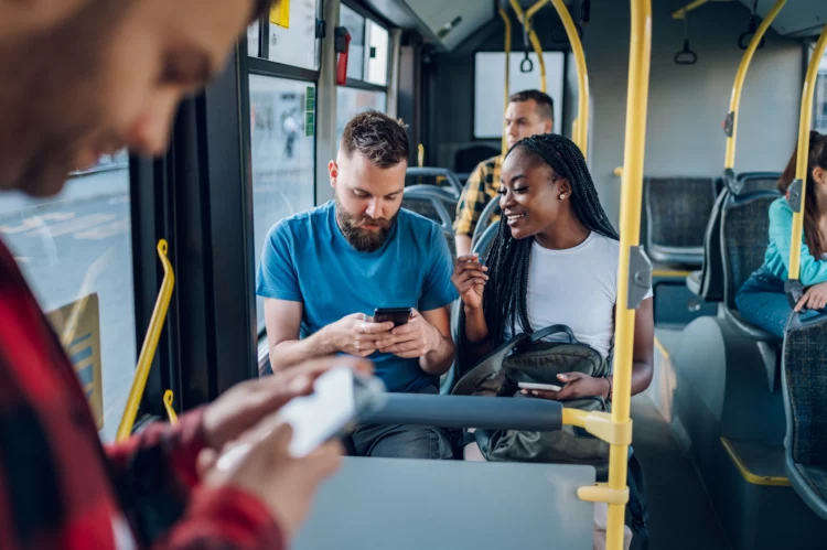 Friends talking and using a smartphone while riding the bus.