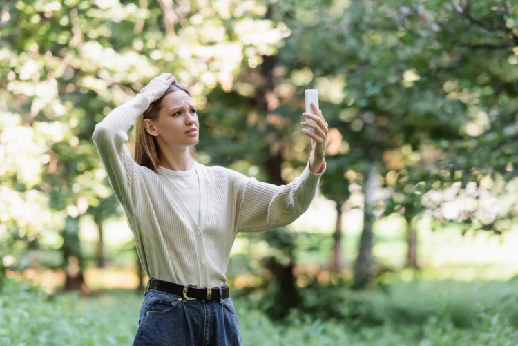 worried young woman with smartphone searching mobile service in park.