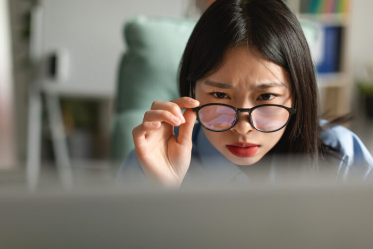 Confused Asian lady using laptop looking at screen