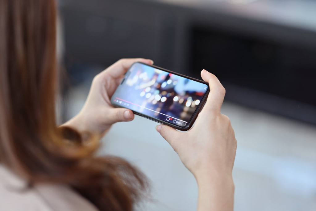 Woman holding mobile phone playing video stream online