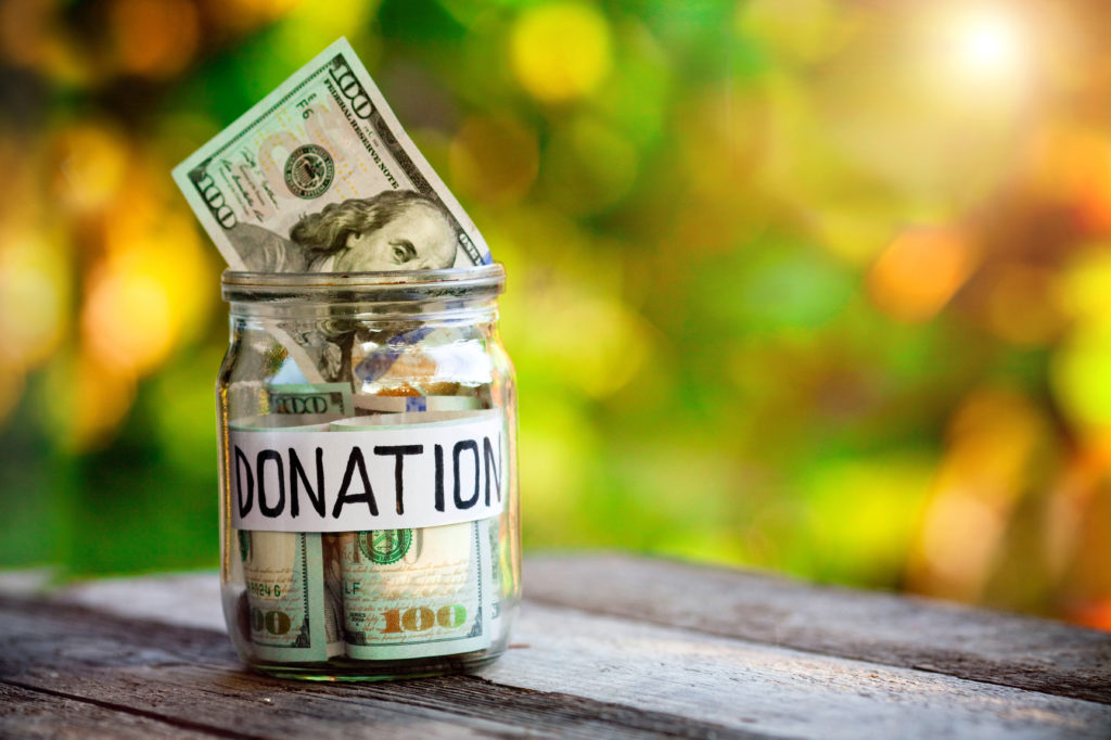 Glass jar with dollars and the word donation paper label. 