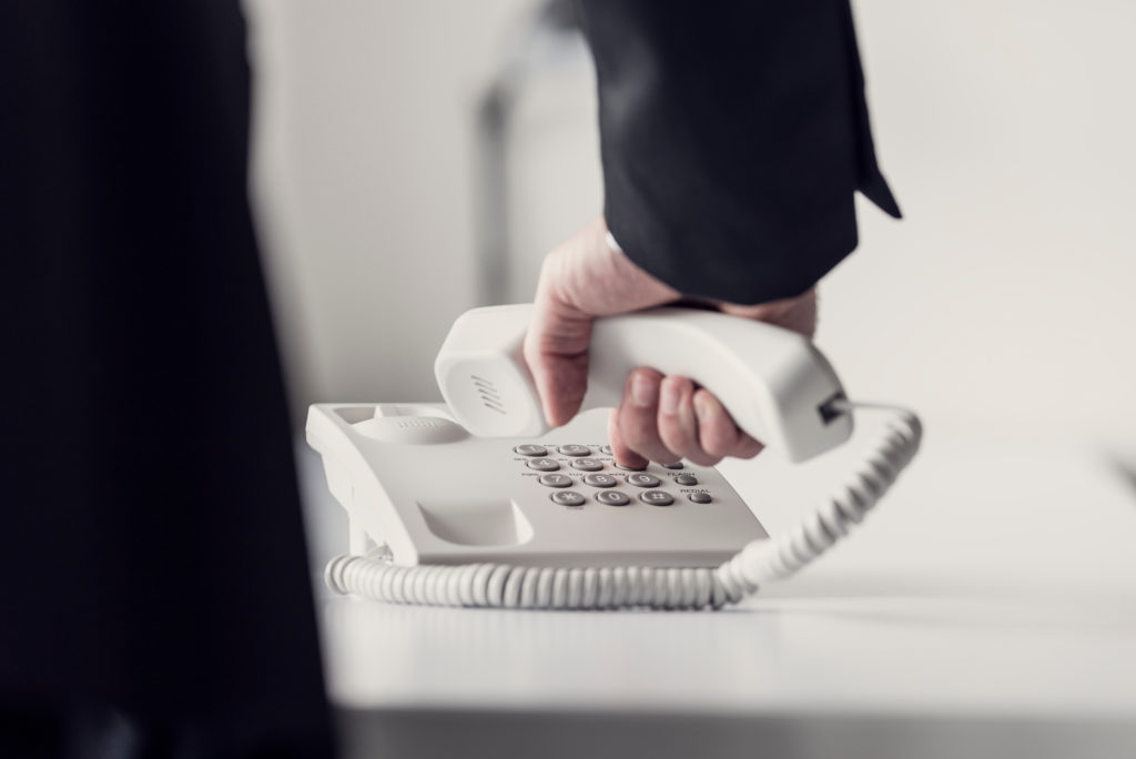 A businessman dialing telephone number on analog phone.