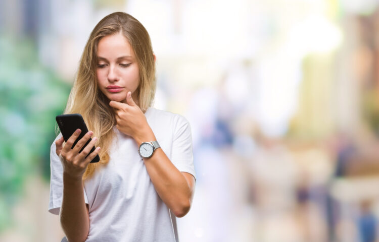 Young beautiful blonde woman using smartphone with serious face thinking 