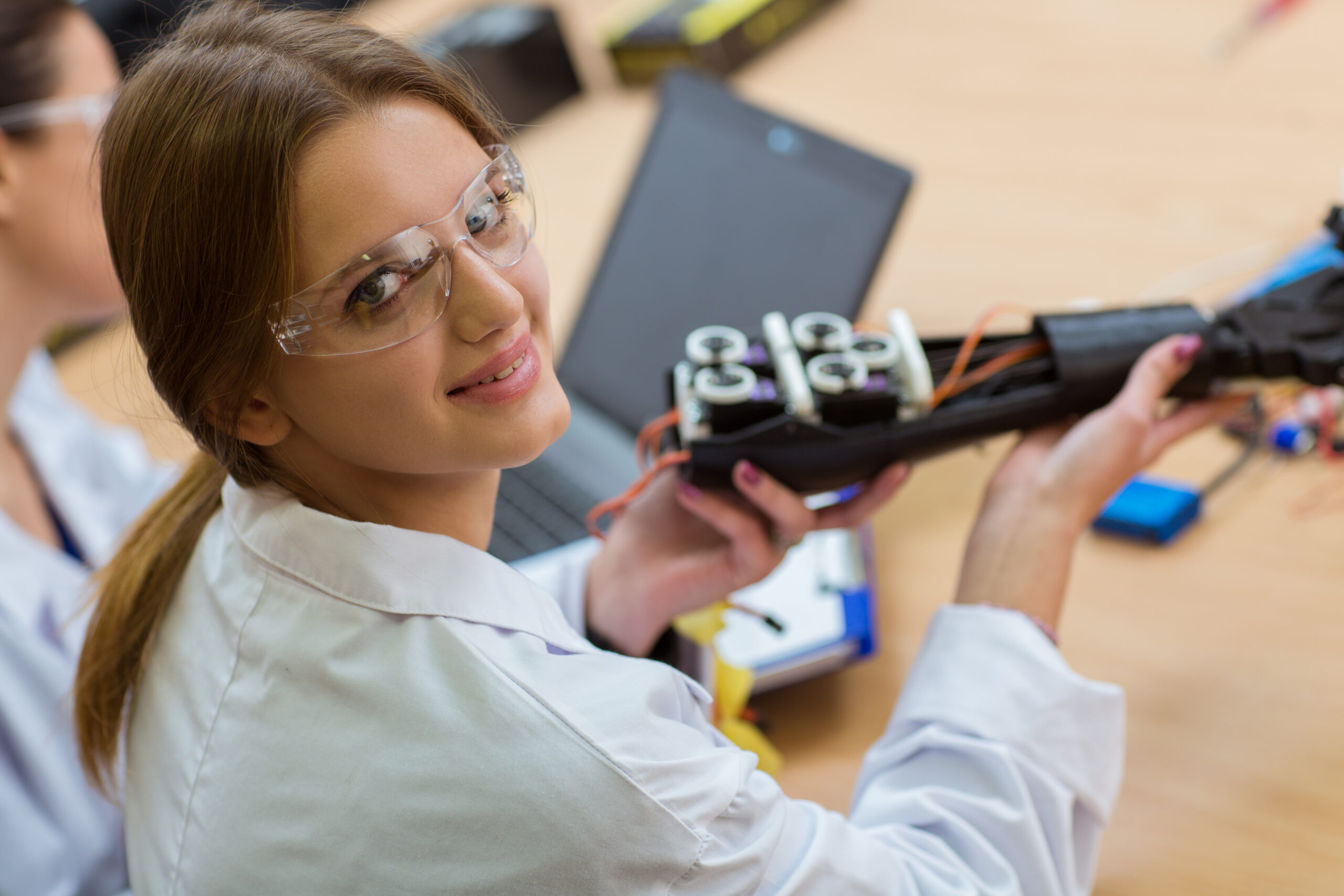 young female scientist holding plastic hand at robotics laboratory
