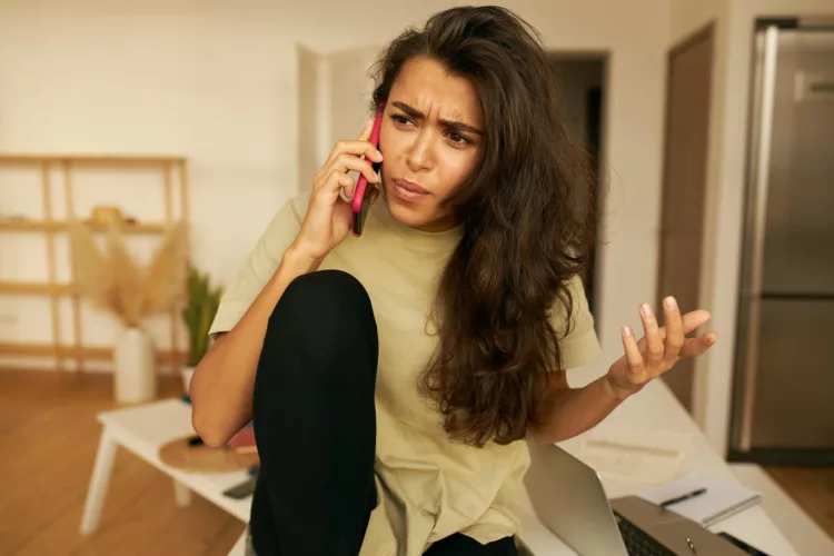 young woman looks frustrated while making a phone call on her mobile phone