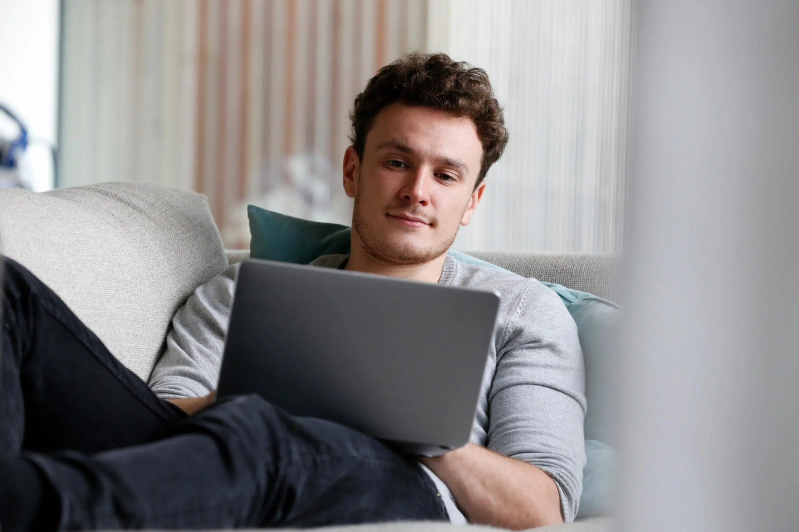 Man relaxing on sofa using laptop computer