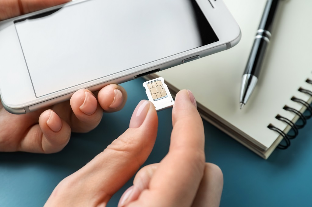 Woman inserting sim card into mobile phone.