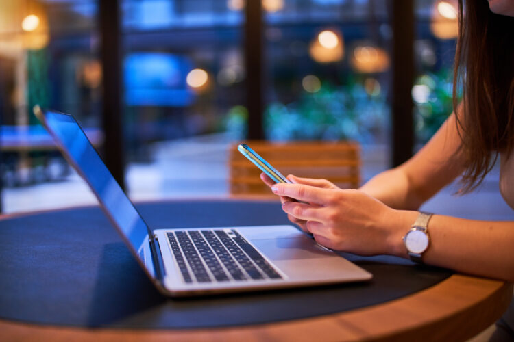 Modern female using phone and laptop in the office.