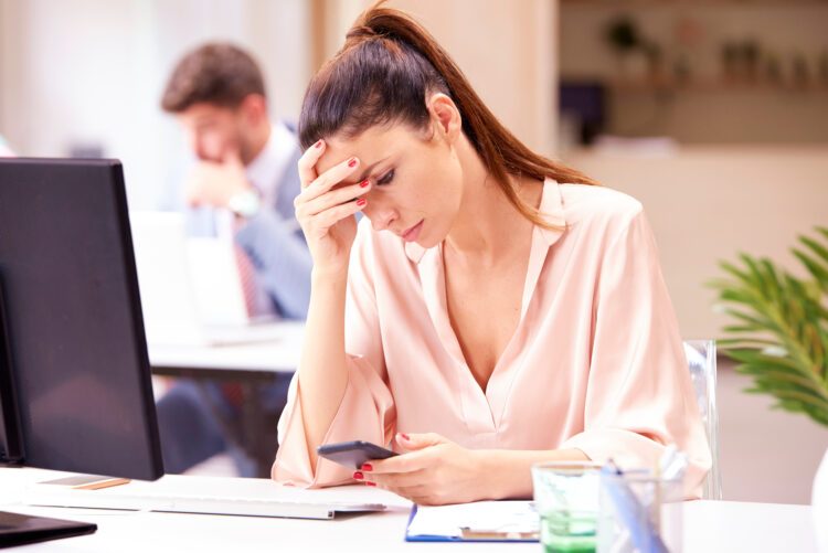 Serious faced woman using cell phone at work