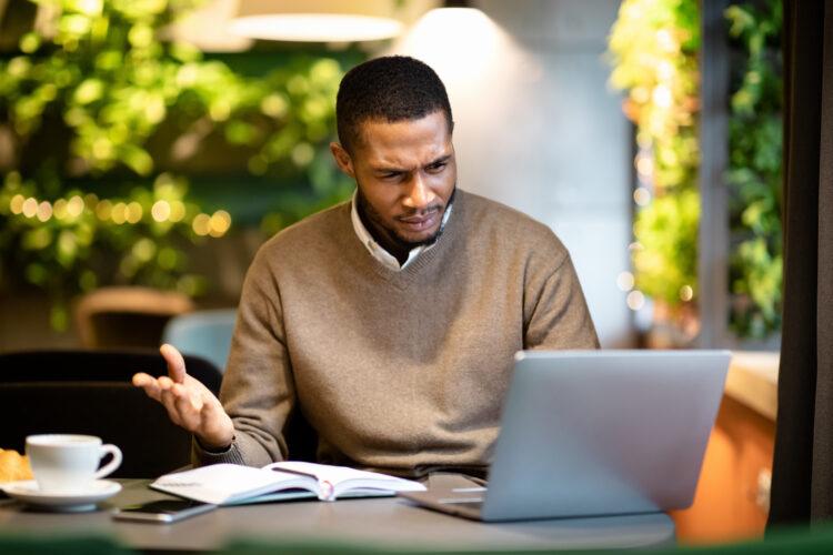 Surprised young black man looking at his computer