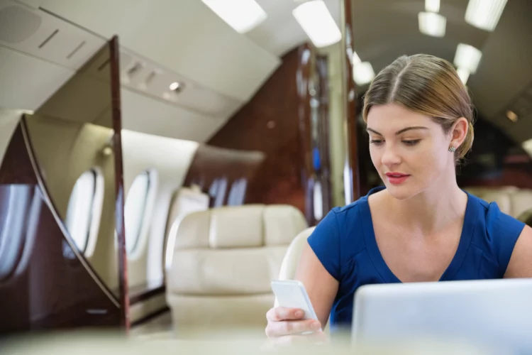 Young businesswoman using smartphone on airplane