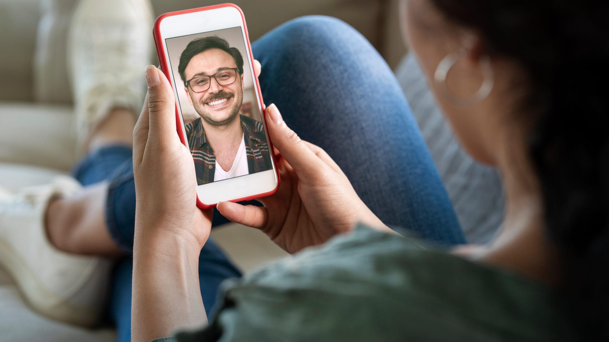 Young woman using smartphone for a video call with male friend