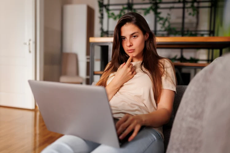 serious looking woman using laptop at home