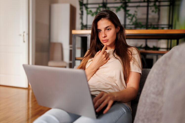 serious looking woman using laptop at home