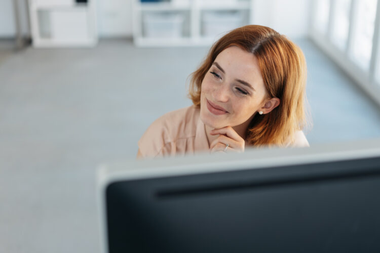 Przemyślana profesjonalna kobieta obserwująca na bok przed komputerem
