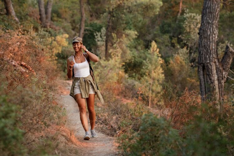 Happy woman using mobile phone while hiking in nature.