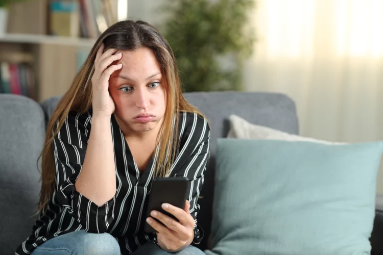  Frustrated woman reading phone content at home