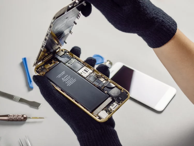 Technician repairing broken smartphone on desk
