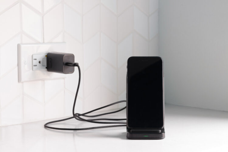 a black smart phone docked in a wireless charging station.