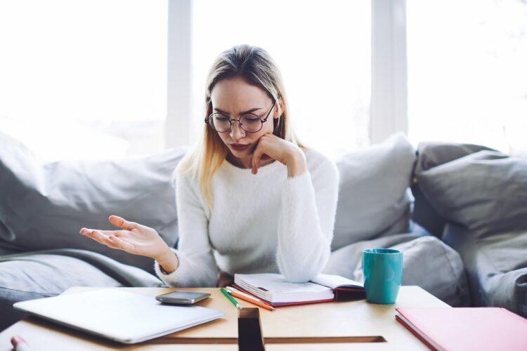 Confused young woman checking smartphone