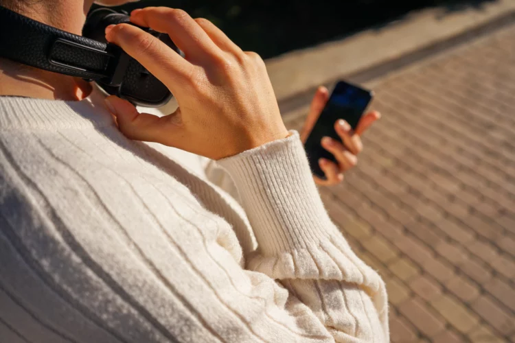 a woman in a white knitted sweater and jeans with a smartphone.
