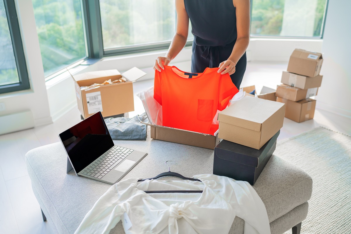 female homebased online seller packing fashion clothing in mailing box for shipping