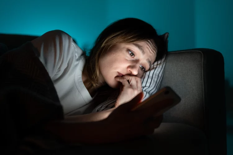 Anxious woman in bed using smartphone at night