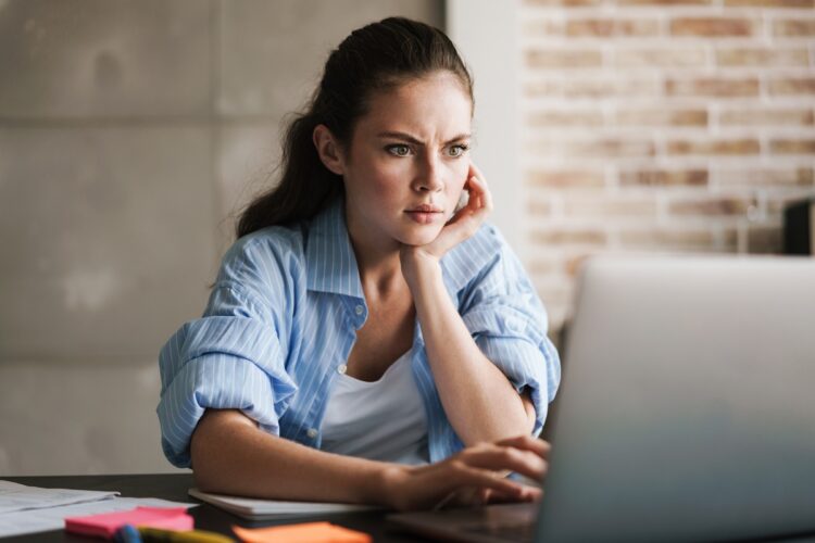 Displeased woman at home using laptop