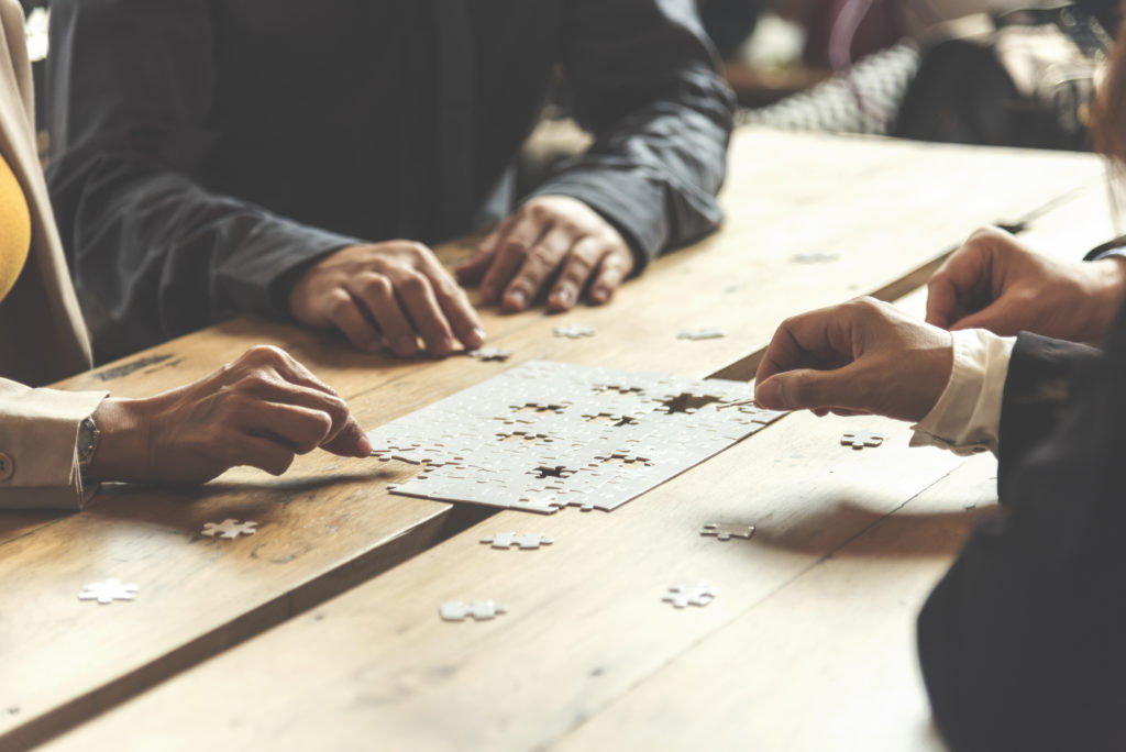 Implement improve puzzel solve connections together with synergy strategy team building organizing connection by trust communication. Hands of stakeholders business trust team holding jigsaw puzzle.