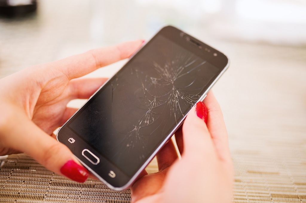 Smartphone with broken screen in woman's hands.