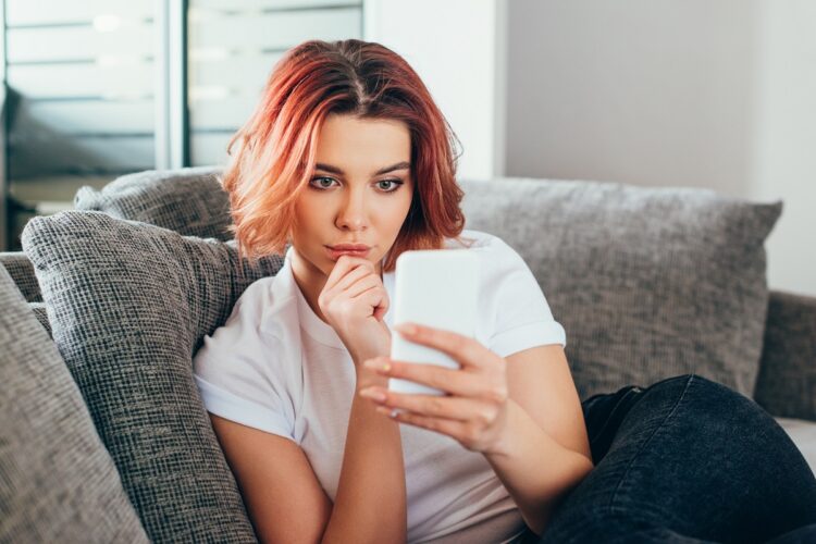 beautiful thoughtful girl using smartphone at home