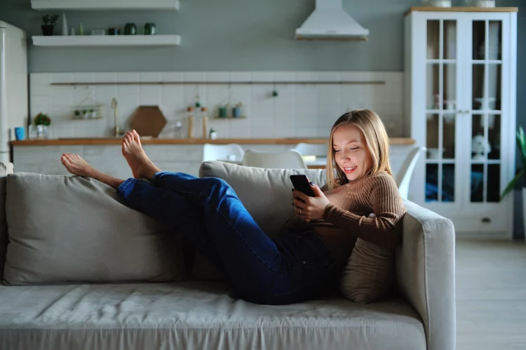 Woman use of smartphone in the evening at home while laying on sofa