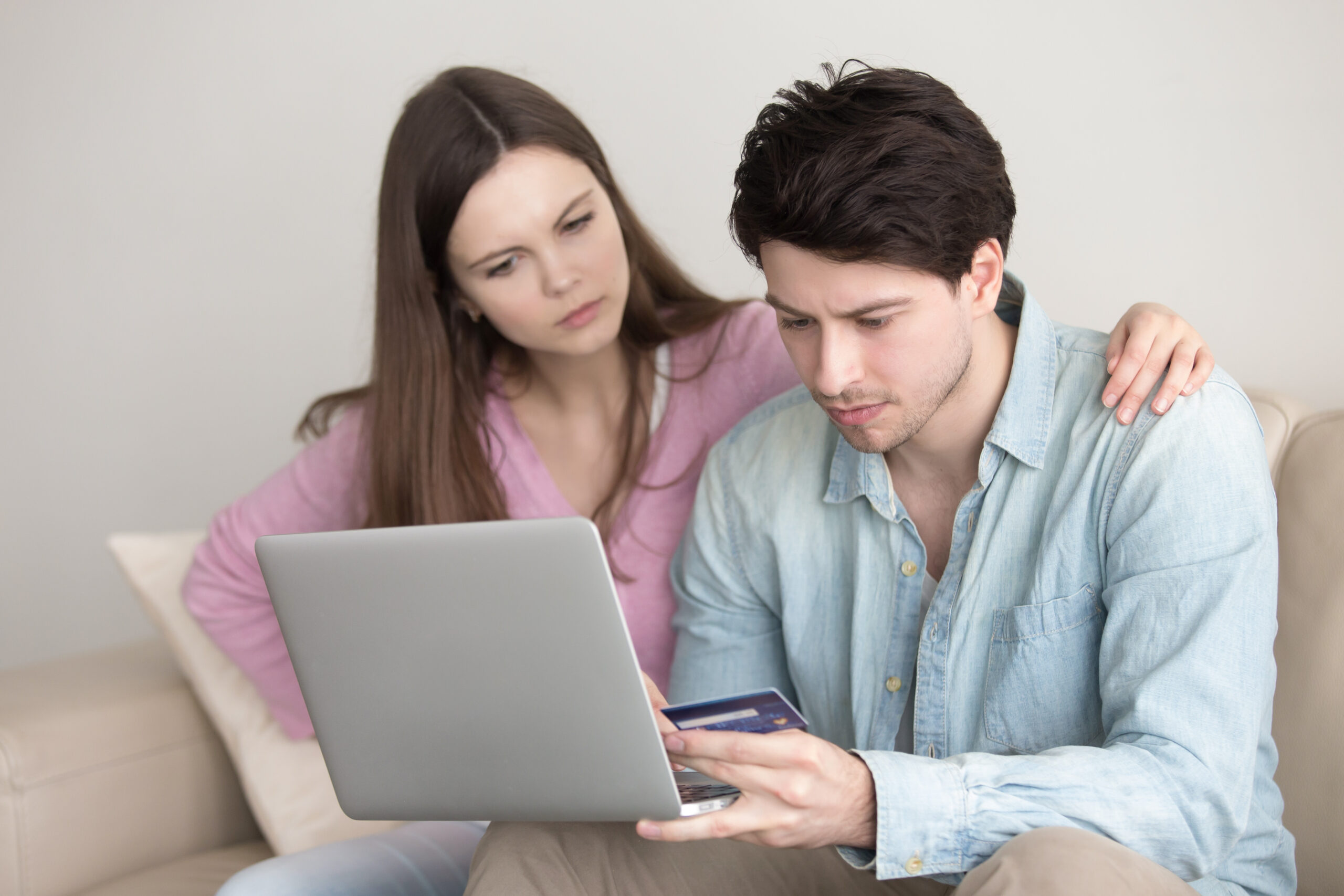 Young couple with serious expression shopping online with credit card