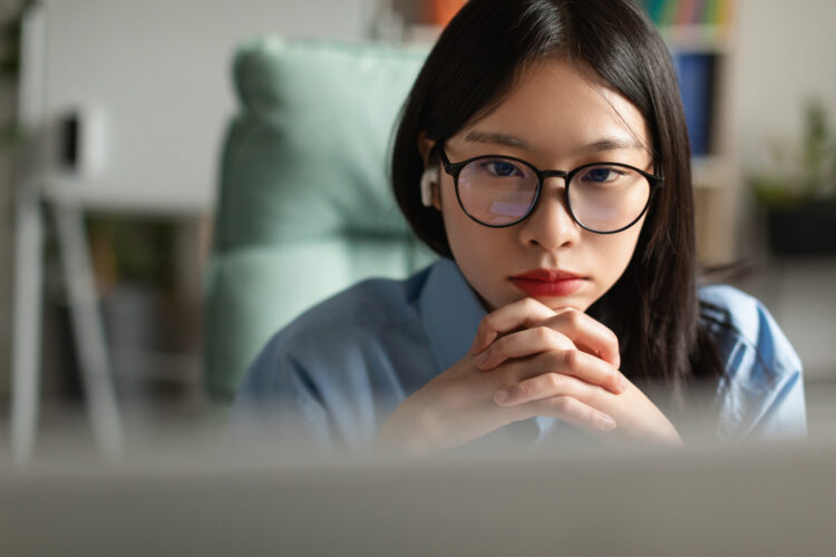 attractive Asian woman using laptop at home office and thinking