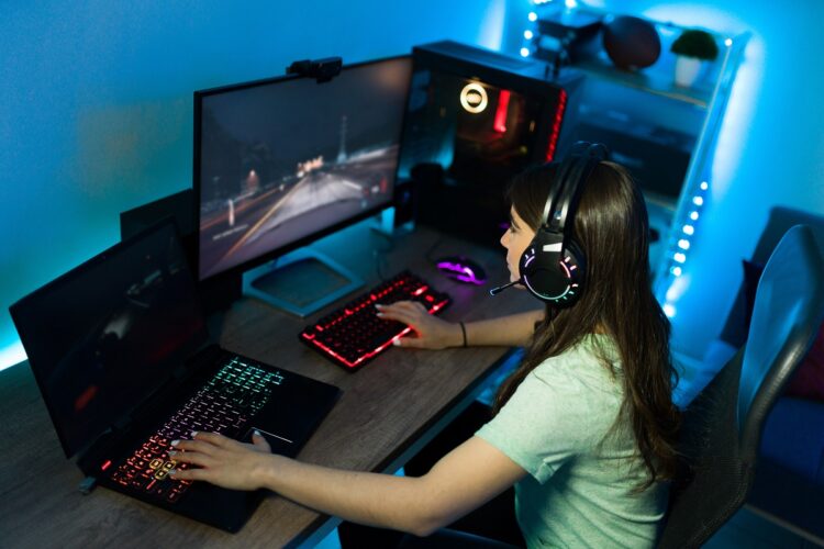 Pretty woman gamer using a gaming PC and laptop