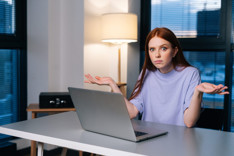 Wanita muda yang frustrasi bingung dengan masalah komputer laptop duduk di meja