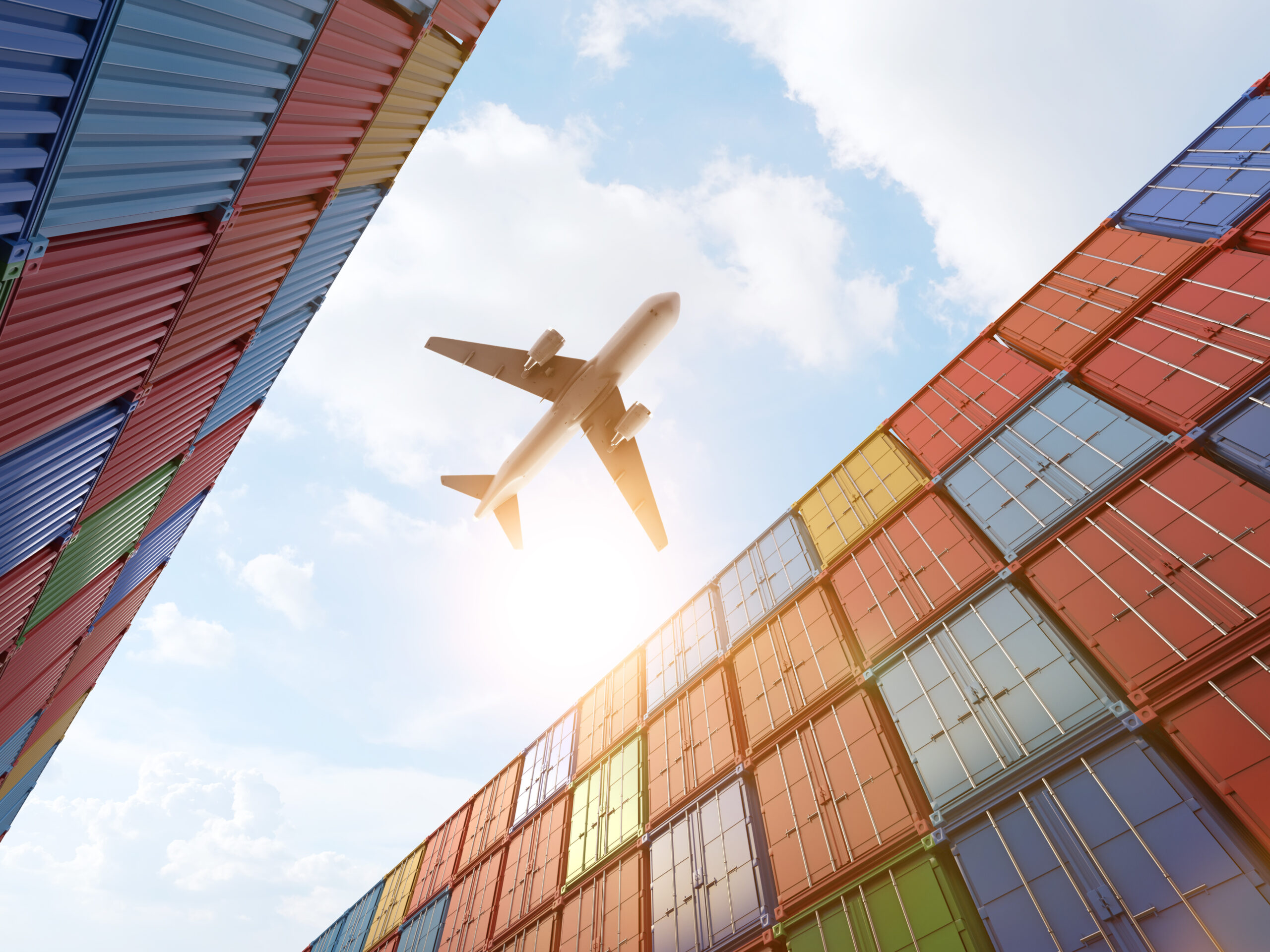 Cargo plane flying above stack of containers at container port