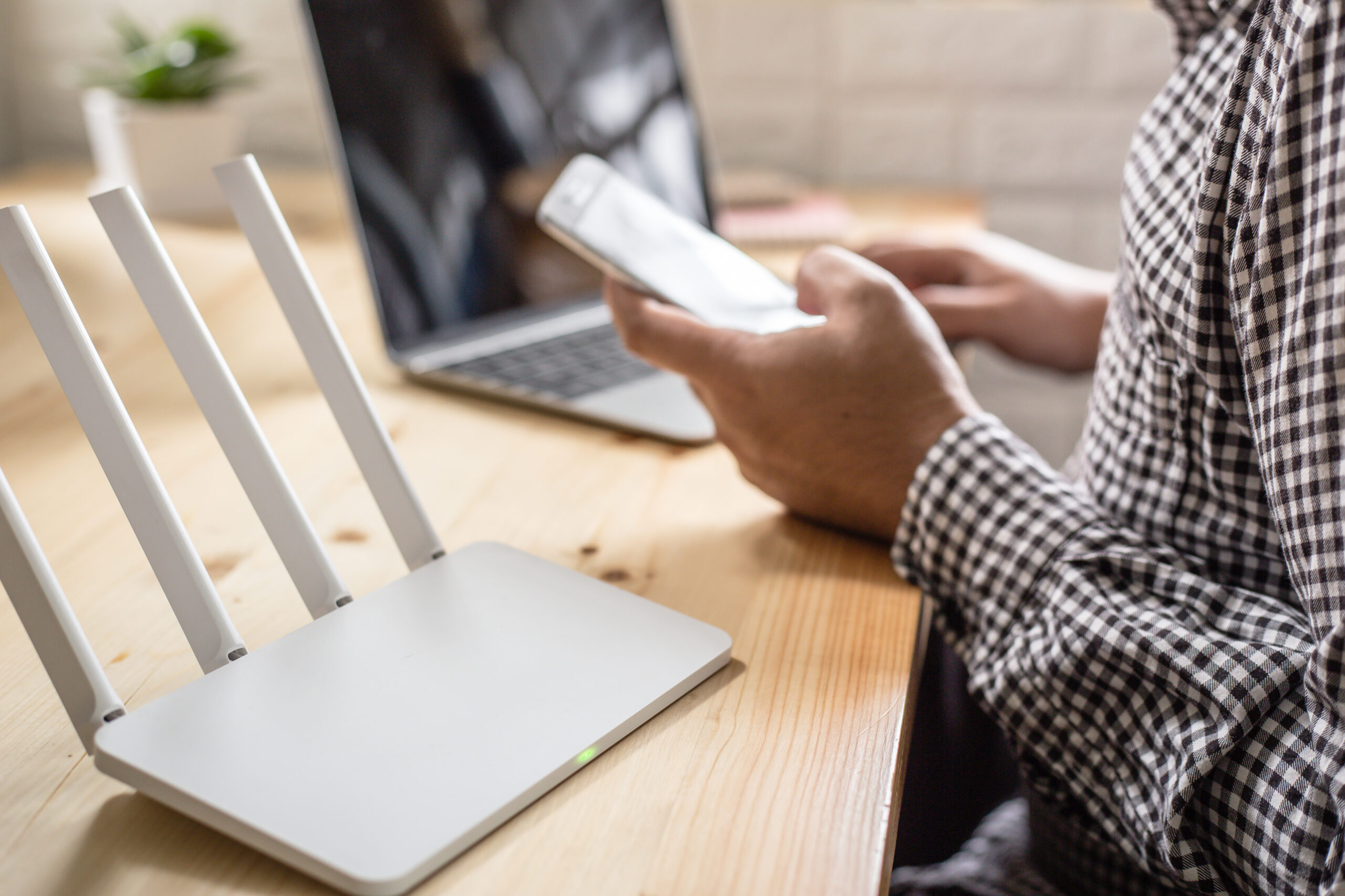 closeup of a wireless router and a man using smartphone on livin