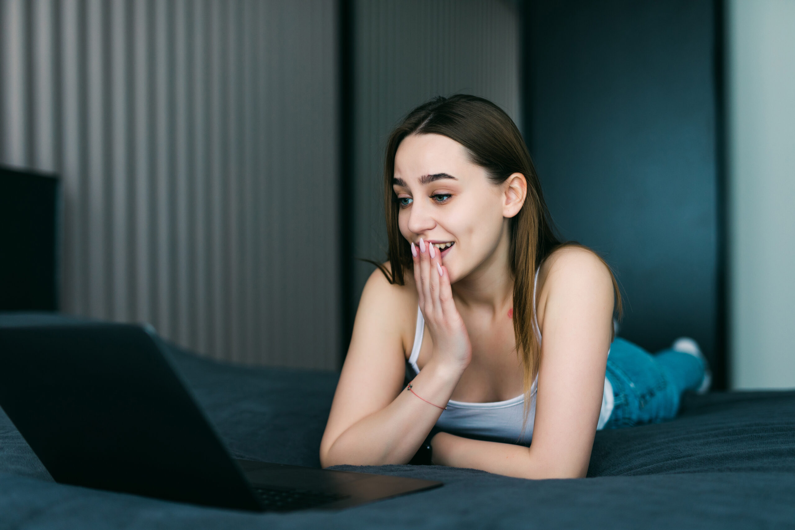 a shocked young attractive woman using laptop in bed