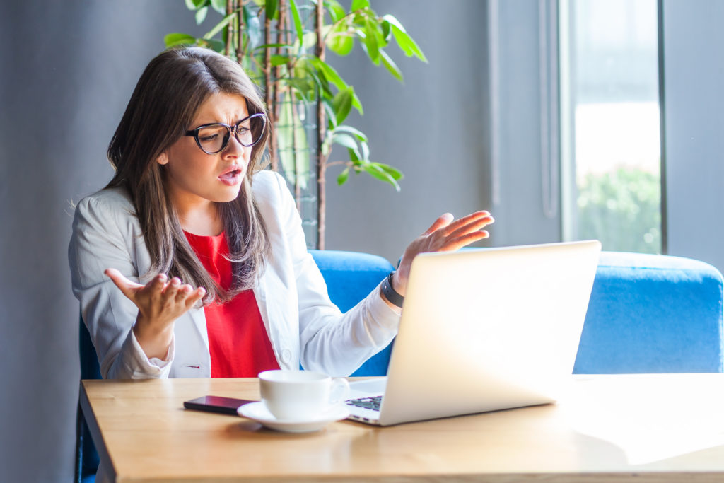 Woman expressing frustration in front of laptop.