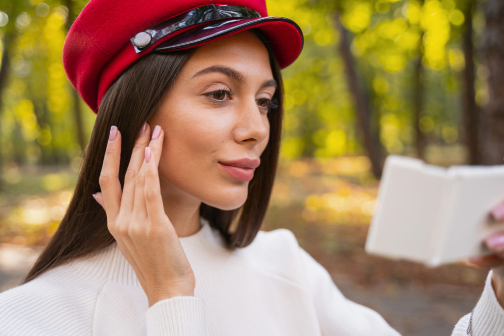 Pretty woman checking her face on the handheld mirror