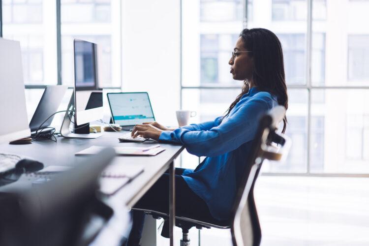 Elegant thoughtful woman working at computer in office